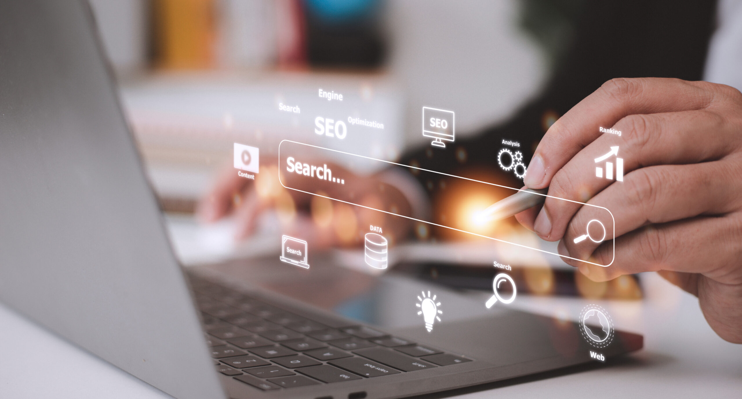 A search bar screen shown above an open laptop showing icons related to SEO and Analitics